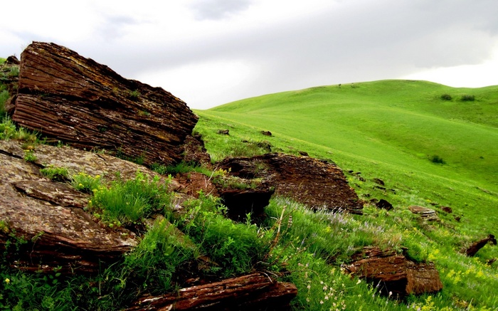 Rocky hills with green grass and cloudy sky