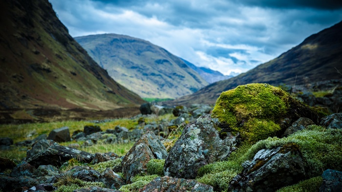 Mossy rocks in a mountain valley under cloudy sky