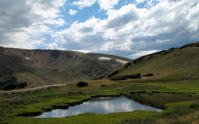 Mountain landscape with a small pond and cloudy sky