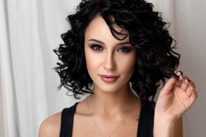 Woman with curly dark hair and makeup