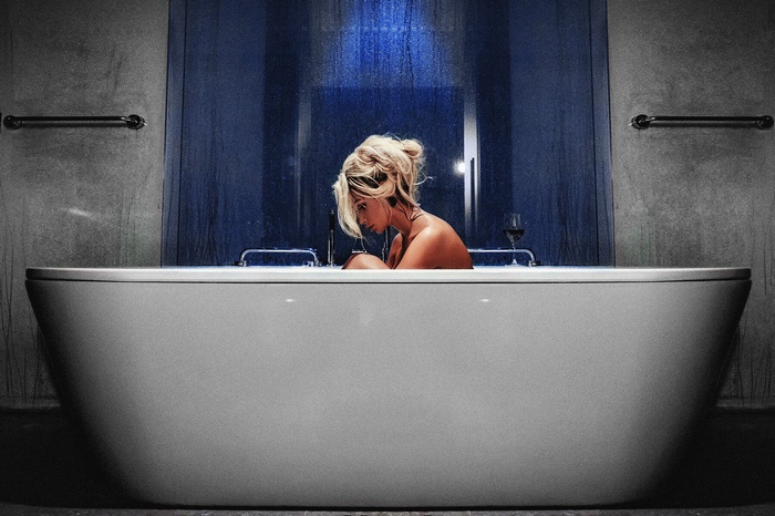 Woman sitting in a bathtub with a glass of wine