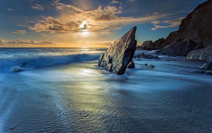 Ocean waves crashing on a rocky coast at sunset