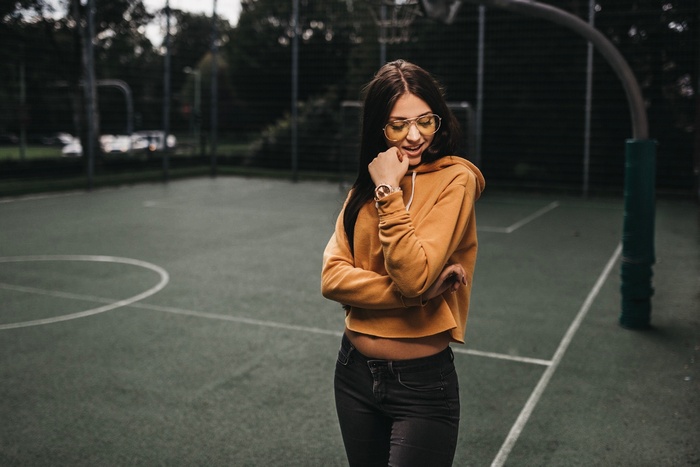 Woman in yellow hoodie and glasses on basketball court