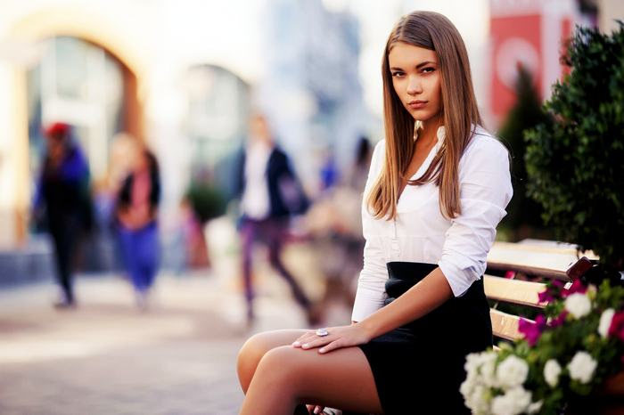 Woman in white shirt and black skirt sitting on a bench
