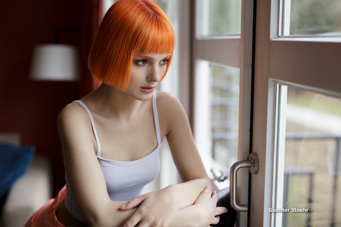 Woman with orange hair by the window