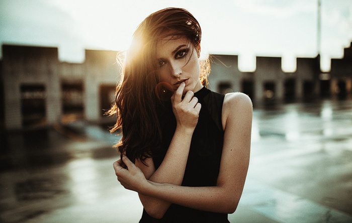Woman with finger on lips in front of building