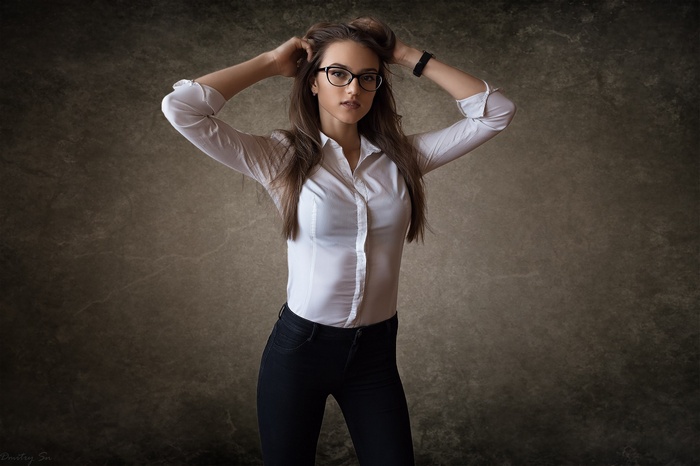 Woman in white shirt and glasses with hands in hair