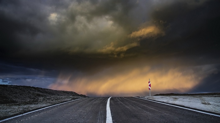 Stormy sky over a road with a warning sign