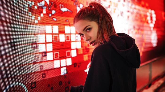 Woman with ponytail in black hoodie looking over shoulder