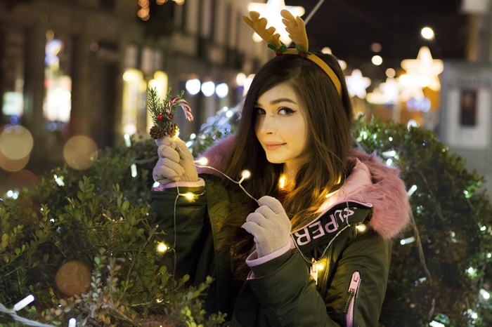 Woman with reindeer antlers holding Christmas ornament