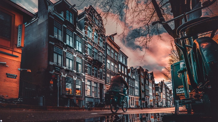 Bicyclist on a wet street in Amsterdam at sunset