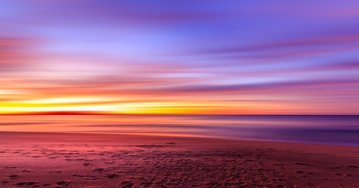 Sunset over the ocean with colorful clouds and beach