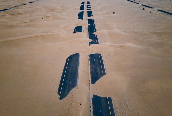 Desert highway partially buried in sand