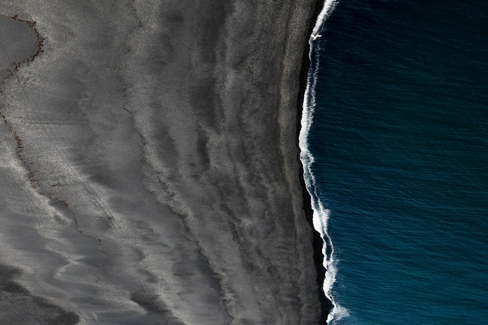 Black sand beach and ocean waves from above