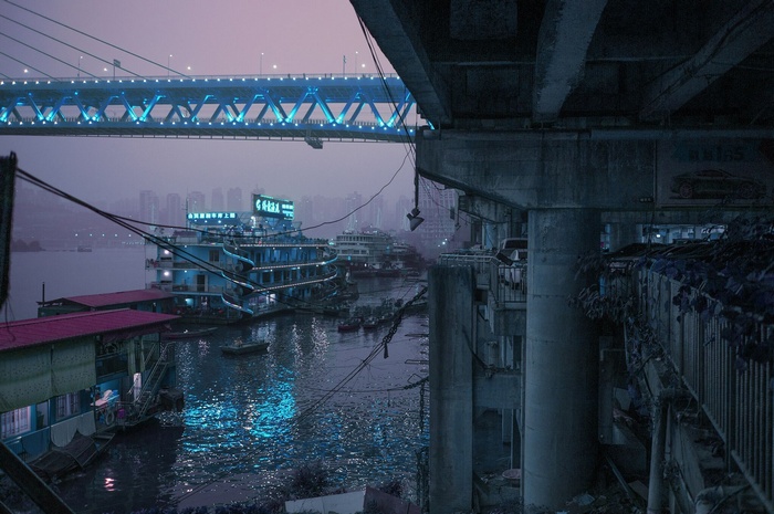 Chongqing cityscape with illuminated bridge and boats at dusk