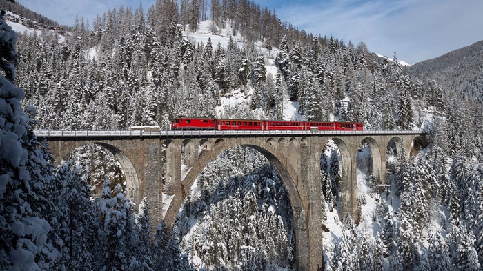 Red train on Wiesen Viaduct in snowy Switzerland