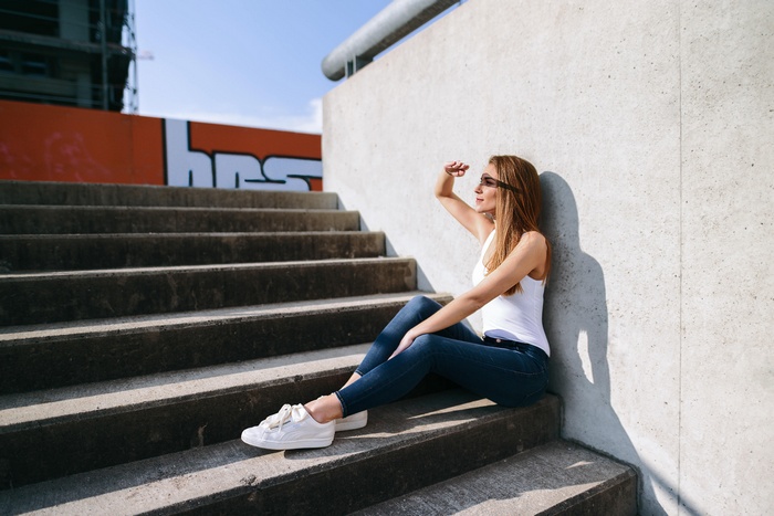 Woman in white top and jeans sitting on stairs