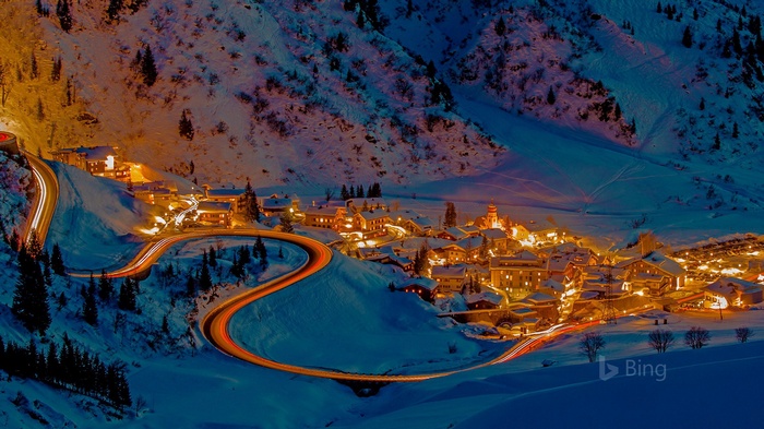 Winding road through a snowy mountain village at night