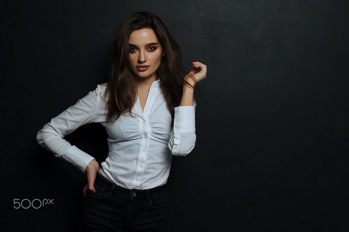 Woman in white shirt and black jeans posing