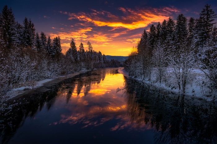 Winter river at sunset with snow-covered trees