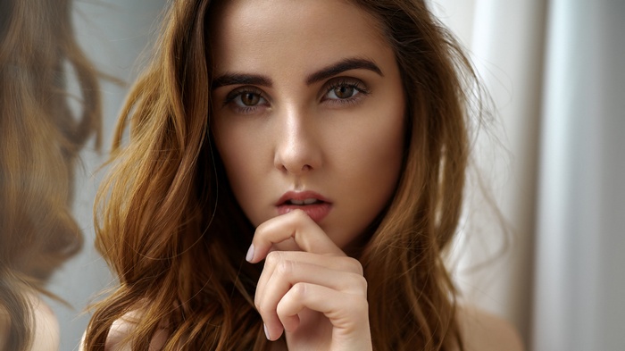 Woman with auburn hair touching her lips