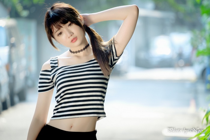 Asian woman with ponytail wearing striped off-the-shoulder shirt
