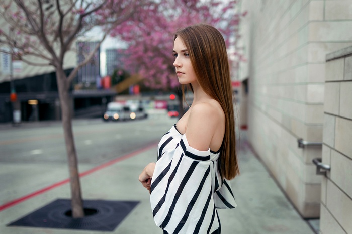 Woman with long brown hair in a striped off-the-shoulder top