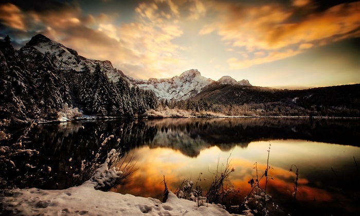 Snowy mountains reflected in a lake at sunset