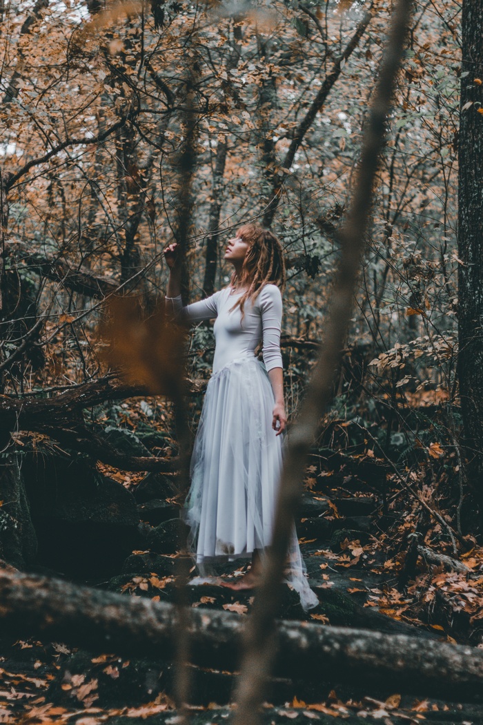 Woman with dreadlocks in a white dress in a forest