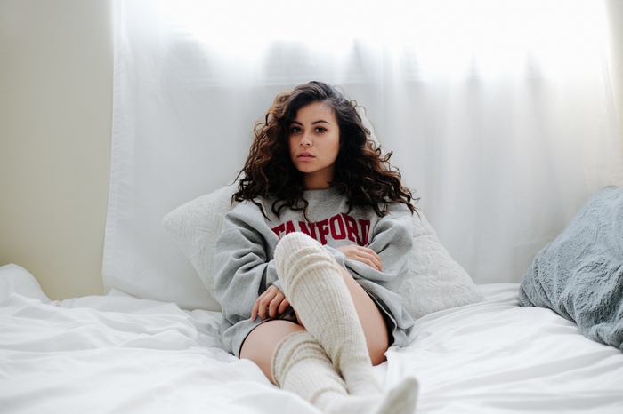 Woman in Stanford sweatshirt and knee-highs on bed