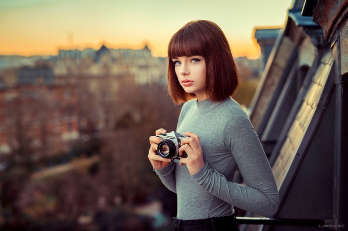 Woman holding a camera with cityscape background
