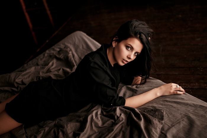 Woman in black clothing lying on a bed