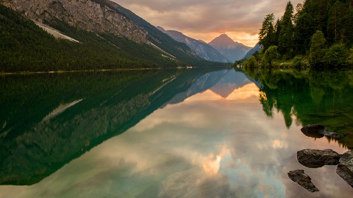 Mountains and forest reflected in a lake at sunset