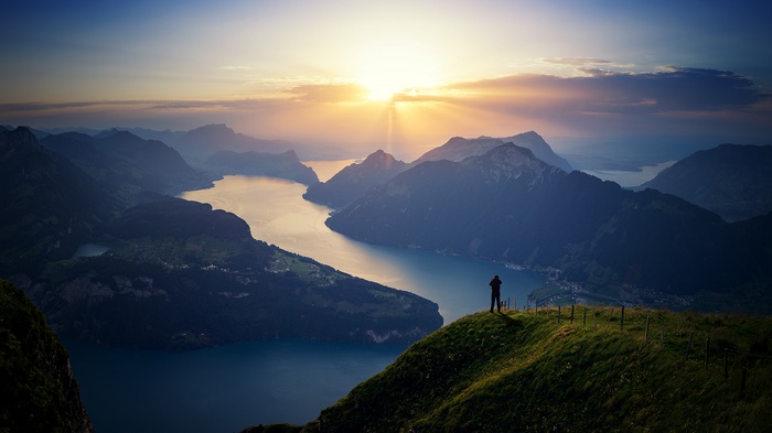 Man photographing a mountain lake at sunset