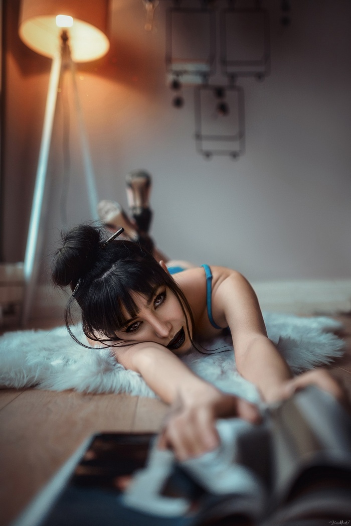 Woman with dark hair and makeup lying on rug