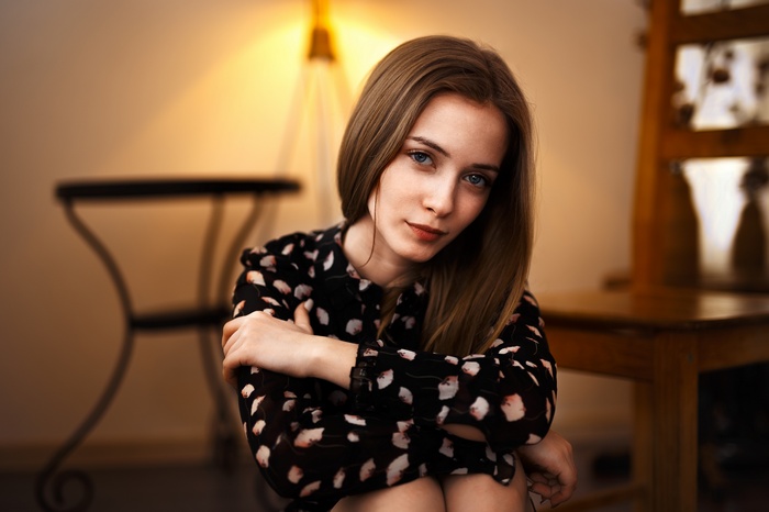 Woman with blonde hair and gray eyes sitting indoors