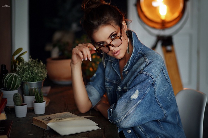 Woman with glasses and denim jacket sitting at a desk