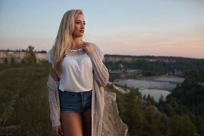 Woman in white top and jean shorts with cardigan outdoors