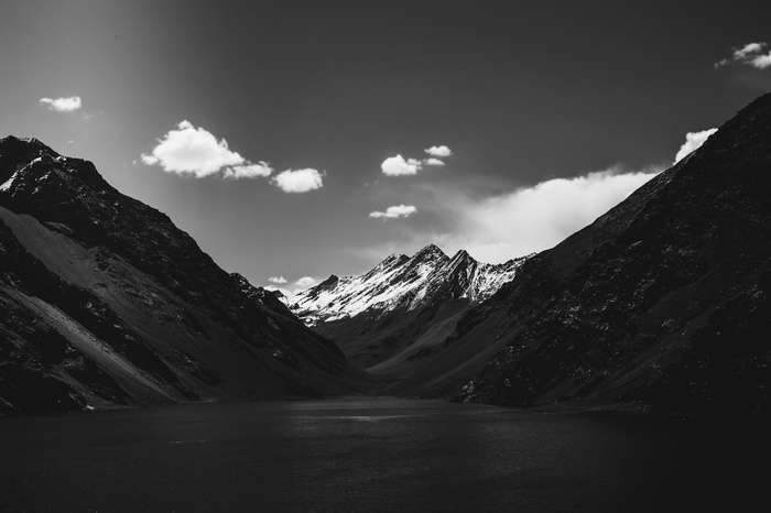 Monochrome mountain landscape with clouds over a lake