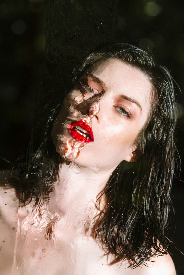 Woman with red lipstick behind water