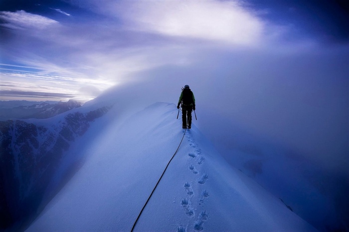 Climber on a snowy mountain ridge in clouds