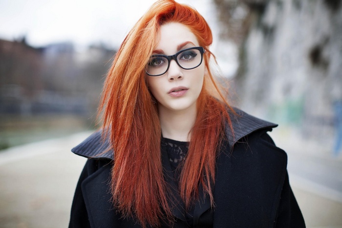 Redhead woman with glasses wearing a black coat