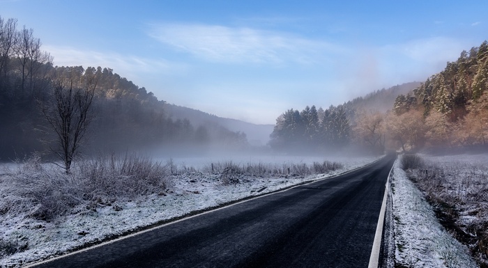 Winter road through a foggy forest landscape