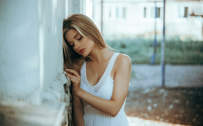 Woman leaning against a wall outdoors