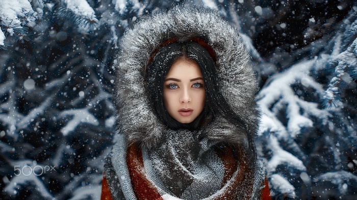 Woman with blue eyes and black hair in a snowy forest