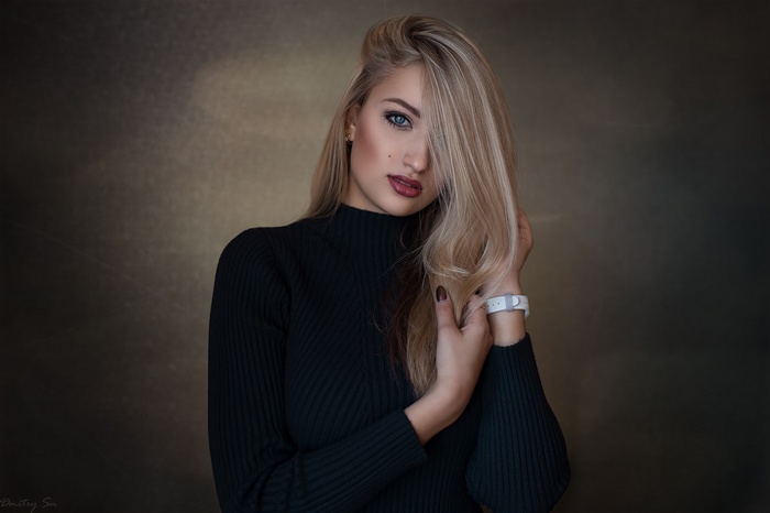 Woman with blonde hair and blue eyes wearing a black turtleneck