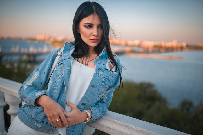 Woman in denim jacket looking away by a river