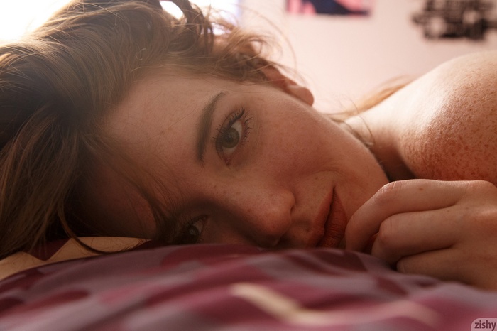 Woman with freckles lying in bed
