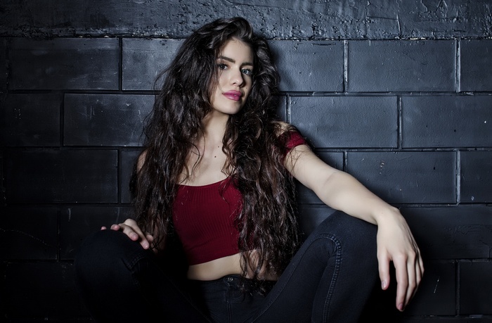 Woman with long dark hair in a red top and black jeans