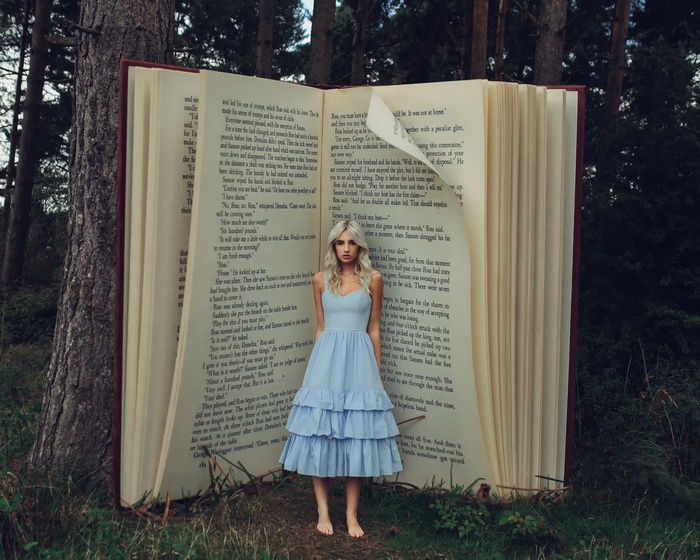 Woman in blue dress in front of giant open book